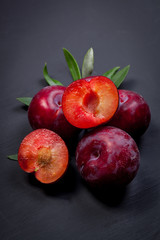 Fresh plums on black wooden table