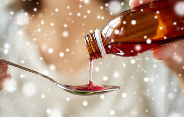 woman pouring medication from bottle to spoon