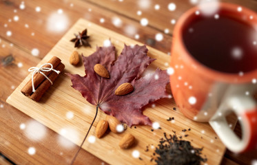 cup of tea, maple leaf and almond on wooden board