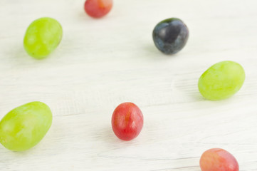 Scattered colored grapes on old wooden rustic white planks