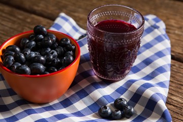 Bowl of blueberries and juice on wooden table