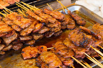 pork on the grill with flame. / Street food in Thailand. / thai style bbq grilled pork./ Grilled pork skewers at night market.