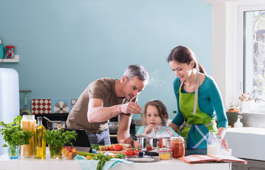 Dad, mom and their daughter cooking a recipe in the kitchen