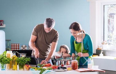 Dad, mom and their daughter cooking a recipe in the kitchen