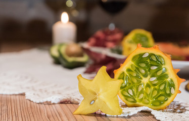 Sternfrucht und Kiwano mit Kerzenlicht im Hintergrund