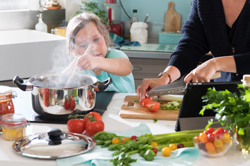 A little girl cooking a recipe in the kitchen with her mother