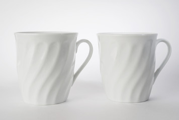 Composition of two white tea mugs, isolated, on background.