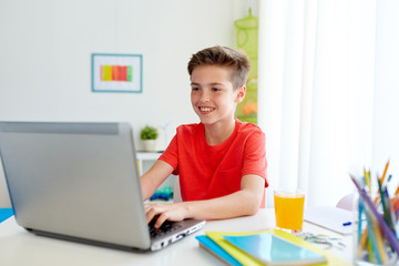 student boy typing on laptop computer at home