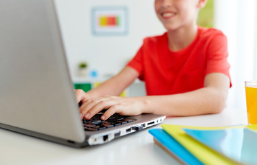 student boy typing on laptop computer at home