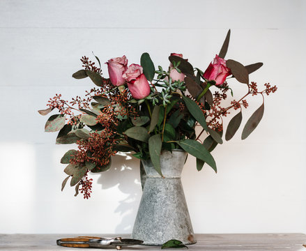 A pretty bouquet of pink toned flowers and foliage in a vintage zinc jug.