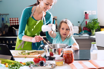 A mother and her daughter cooking a recipe in the kitchen