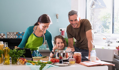 Dad, mom and their daughter cooking a recipe in the kitchen