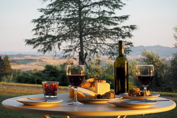a dinner with wine, bread and cheese at a covered table in the garden