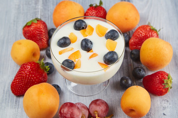 Strawberries, blueberries, apricot with yoghurt on a wooden board