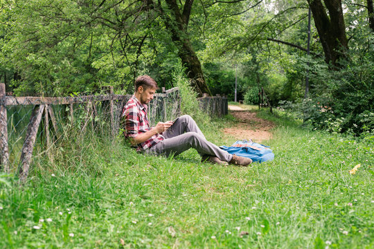 Man sitting and reading alone in a park underneath trees