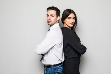 Concept of partnership in business. Young man and woman standing back-to-back with crossed hands against gray background