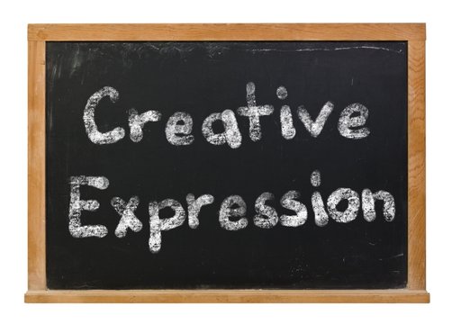 Creative expression written in white chalk on a black chalkboard isolated on white