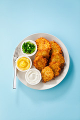 Potato pancakes, latkes or boxty and sauces from sour cream, yogurt, apple sauce and finely chopped green onion isolated on a blue background
