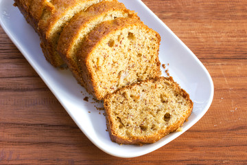 Banana cake. Sliced homemade banana cake on whit plate. Delicious dessert for eat with tea or coffee. Top view on wooden table.