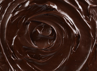 Texture of dark chocolate icing swirl close up. Food background