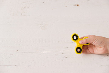 Child's hand spinning a fidget spinner device. Top view. Playing with a yellow hand spinner fidget...