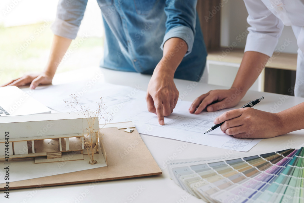 Poster Two interior design or graphic designer at work on project of architecture drawing with work tools and color swatches, colour chart, color samples for selection, renovation and technology concept