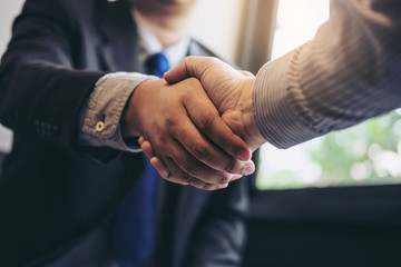Two business men shaking hands during a meeting to sign agreement and become a business partner,...