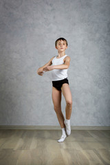 Little ballet caucasian boy dancing in a studio in white shirt and black underpants ballet uniform. Full-length portrait.