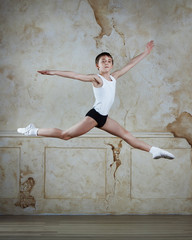 Little ballet caucasian boy dancing in a studio in white shirt and black underpants ballet uniform. Full-length portrait.