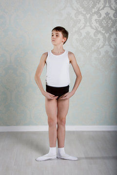Little ballet caucasian boy dancing in a studio in white shirt and black underpants ballet uniform. Full-length portrait.