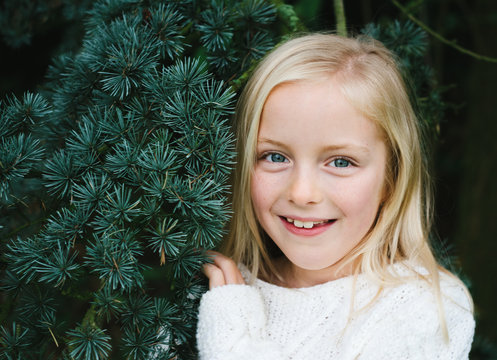 A smiling little girl and a fir tree. - Powered by Adobe
