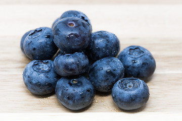 Close up of fresh Blueberries on wooden chopping board, sprayed with water.