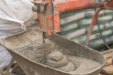 Construction worker mixing ingredients in the concrete mixer at building site