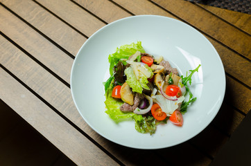 Fresh salad with chicken breast, arugula and tomato.