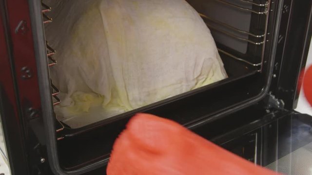 Thanksgiving turkey cooked in cheesecloth. Placing 20 lb row turkey in hot oven. Cheese cloth basted with melted butter and wine. Thanksgiving or Christmas roast turkey recipe.