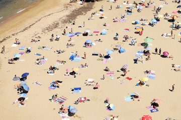 Fototapeta na wymiar gente con sombrillas tomando el sol en la playa vista desde arriba