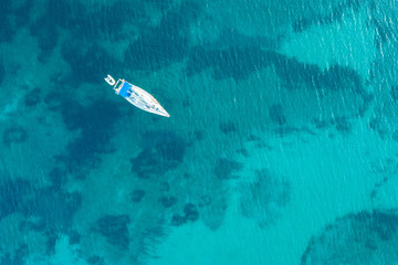 Beautiful beach, coast and bay with crystal clear sea water and a sailing yacht seen from above