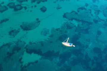 Beautiful beach, coast and bay with crystal clear sea water and a sailing yacht seen from above