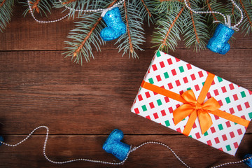 Christmas composition. Spruce branches, blue Christmas decorations, gift on a wooden brown background. Space for text, top view. Background