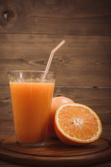 Orange juice in glass and fresh fruits on wooden background