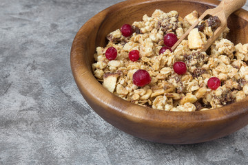 Granola muesli and cranberry berries for breakfast natural on a gray marble background with copy space, concept of a healthy diet