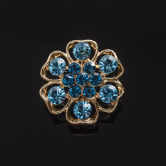 gold round brooch with blue diamonds isolated on black