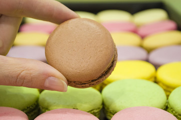 female hand taking tasty colorful macaroons from box