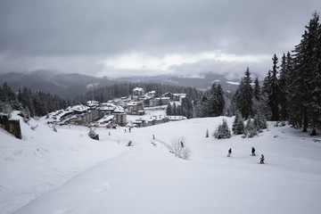 Fototapeta na wymiar Pamporovo ski resort, Bulgaria. Winter view from the ski slope to the Studenetz ski lift and hotels.