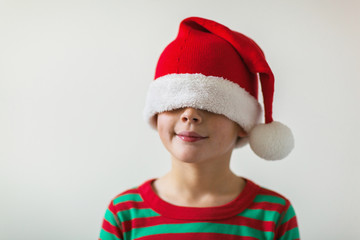 smiling boy with a santa hat pulled over his eyes