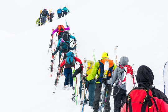 Group of cross-country skiers ascending a steep slope.