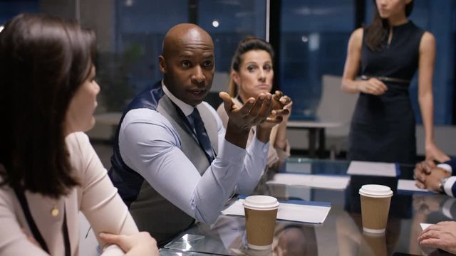  Businesswoman giving presentation to colleagues in late meeting