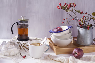 the Still-life with a hawthorn, a cup of tea and a kettle on a white wooden background