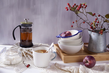 the Still-life with a hawthorn, a cup of tea and a kettle on a white wooden background