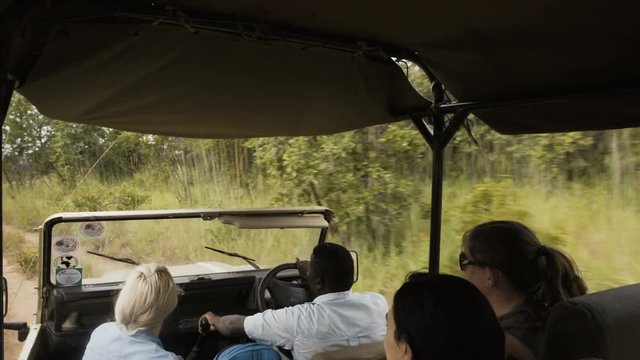  People in safari vehicle traveling through national park in Zambia, Africa